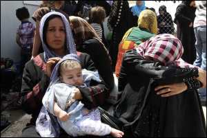 Families fleeing the violence in the Iraqi city of Mosul wait at a checkpoint in outskirts of Arbil